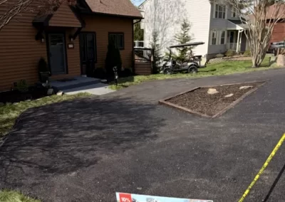 Freshly paved driveway in front of a house with an Ace Paving sign and construction tape in the yard.