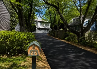 A newly paved driveway leads to a house, with a green mailbox labeled "UPHALLS" in the foreground.
